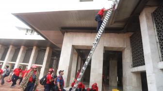 Sejumlah petugas Damkar membersihkan Gereja Katedral dan Masjid Istiqlal di Jakarta, Selasa (12/2). [Suara.com/Muhaimin A Untung]