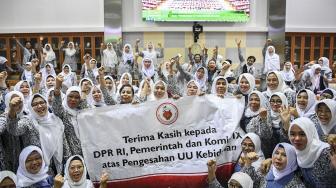 Sejumlah bidan meluapkan kegembiraan saat menonton pengesahaan UU tentang Kebidanan pada rapat paripurna DPR dari ruang rapat Komisi IX DPR di Kompleks Parlemen, Senayan, Jakarta, Rabu (13/2). [ANTARA FOTO/Hafidz Mubarak]