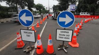 Petugas mengatur lalu lintas saat diadakan uji coba sistem satu arah di Dukuh Bawah, Setiabudi, Jakarta Selatan, Rabu (13/2). [Suara.com/Muhaimin A Untung]