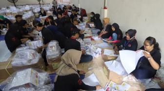 Petugas melipat surat suara di Gudang logistik KPU Komplek Pergudangan Zoodia, Jakarta, Minggu (17/2). [Suara.com/Muhaimin A Untung]