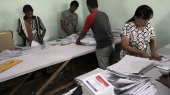 Sejumlah petugas melipat surat suara pemilu di Kantor KPU Jakarta Pusat, Kamis (21/2). [Suara.com/Fakhri Hermansyah]