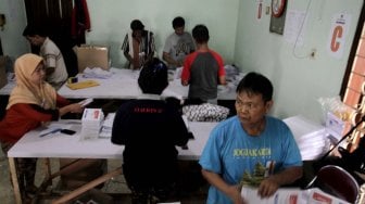 Sejumlah petugas melipat surat suara pemilu di Kantor KPU Jakarta Pusat, Kamis (21/2). [Suara.com/Fakhri Hermansyah]