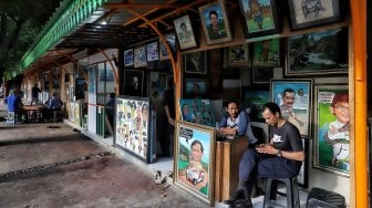 Pelukis sedang berada di kios Sentra Lukisan di kawasan Pasar Baru, Jakarta, Jumat (22/2). [Suara.com/Muhaimin A Untung]