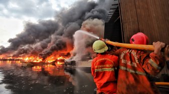 Petugas pemadam kebakaran tampak berusaha memadamkan api pada kapal nelayan yang terbakar di Pelabuhan Muara Baru, Jakarta, Sabtu (23/2/2019).