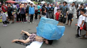 Sejumlah Aktivis melakukan aksi teatrikal bertemakan lingkungan pada Hari bebas kendaraan bermotor (HBKB)  di Bundaran HI, Jakarta Pusat , Minggu (24/2). (Suara.com/Fakhri Hermansyah)