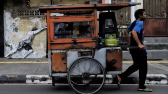 Warga melintas di depan mural kawasan Berok, Penjaringan, Jakarta Utara, Minggu (24/2). [Suara.com/Muhaimin A Untung]