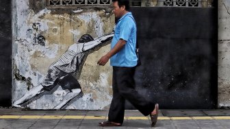 Warga melintas di depan mural kawasan Berok, Penjaringan, Jakarta Utara, Minggu (24/2). [Suara.com/Muhaimin A Untung]