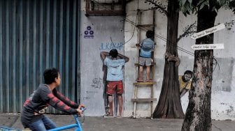 Warga melintas di depan mural kawasan Berok, Penjaringan, Jakarta Utara, Minggu (24/2). [Suara.com/Muhaimin A Untung]