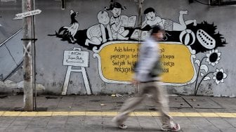 Warga melintas di depan mural kawasan Berok, Penjaringan, Jakarta Utara, Minggu (24/2). [Suara.com/Muhaimin A Untung]