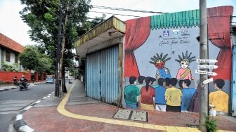 Warga melintas di depan mural kawasan Berok, Penjaringan, Jakarta Utara, Minggu (24/2). [Suara.com/Muhaimin A Untung]