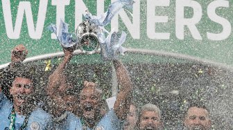 Bek Manchester City Vincent Kompany mengangkat trofi Piala Liga Inggris saat merayakan kemenangan mereka dalam pertandingan sepak bola final Piala Liga Inggris antara Manchester City melawan Chelsea di Stadion Wembley, London, Inggris, Minggu (24/2).[Adrian DENNIS / AFP]