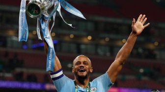 Bek Manchester City Vincent Kompany mengangkat trofi Piala Liga Inggris saat merayakan kemenangan mereka dalam pertandingan sepak bola final Piala Liga Inggris antara Manchester City melawan Chelsea di Stadion Wembley, London, Inggris, Minggu (24/2).[Adrian DENNIS / AFP]