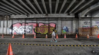 Warga melintas di samping proyek pedestrian Jalan Kendal di bawah Flyover Jalan Sudirman, Dukuh Atas, Jakarta, Selasa (5/3). [Suara.com/Muhaimin A Untung]