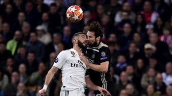 Pemain depan Real Madrid, Karim Benzema dan pemain belakang Ajax Daley Blind melompat untuk merebut bola pada pertandingan leg kedua babak 16 besar Liga Champions antara Real Madrid melawan Ajax Amsterdam di Stadion Santiago Bernabeu, Madrid, Spanyol, Rabu (6/3) dini hari WIB. [JAVIER SORIANO / AFP]