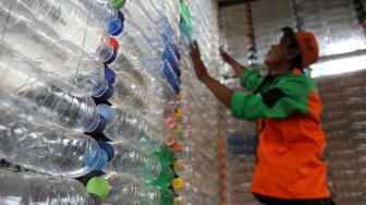 Petugas Unit Pengelola Kegiatan (UPK) Badan Air Dinas Lingkungan Hidup DKI Jakarta menunjukkan botol plastik yang disusun membentuk bangunan posko di kawasan Ciracas, Jakarta Timur, Rabu (13/3). [Suara.com/Arief Hermawan P]