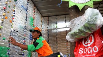 Petugas Unit Pengelola Kegiatan (UPK) Badan Air Dinas Lingkungan Hidup DKI Jakarta menunjukkan botol plastik yang disusun membentuk bangunan posko di kawasan Ciracas, Jakarta Timur, Rabu (13/3). [Suara.com/Arief Hermawan P]