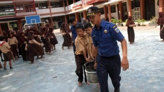 Petugas Suku Dinas Pemadam Kebakaran (Damkar) Jakarta Selatan bersama sejumlah siswa melakukan simulasi pemadaman kebakaran di SDN Kebagusan 01 Pagi, Rabu (20/3). [Suara.com/Arief Hermawan P]