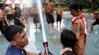 Petugas Suku Dinas Pemadam Kebakaran (Damkar) Jakarta Selatan bersama sejumlah siswa melakukan simulasi pemadaman kebakaran di SDN Kebagusan 01 Pagi, Rabu (20/3). [Suara.com/Arief Hermawan P]