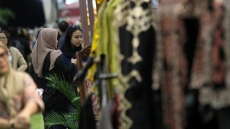 Pengunjung memperhatikan beragam produk batik dan tenun di sejumlah stan pada pameran Adiwastra di JCC, Jakarta, Sabtu (23/3).  [Suara.com/Arief Hermawan P]