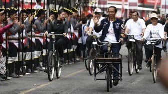 Calon Presiden petahana Joko Widodo (tengah) bersama istri Iriana Joko Widodo (kanan) bersepeda onthel menuju lokasi Deklarasi Alumni Jogja Satukan Indonesia di Stadion Kridosono, Yogyakarta, Sabtu (23/3).  [ANTARA FOTO/Puspa Perwitasari]