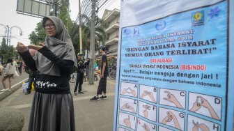 Seorang pegiat sosial melakukan sosialisasi bahasa isyarat saat Hari Bebas Kendaraan Bermotor (HBKB) di Dago, Bandung, Jawa Barat, Minggu (24/3). ANTARA FOTO/Raisan Al Farisi