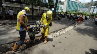 Pekerja melakukan pembongkaran beton pembatas jalan di Jalan M Yamin bagian sisi barat, Menteng, Jakarta, Senin (25/3).[Suara.com/Muhaimin A Untung]