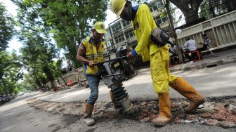 Pekerja melakukan pembongkaran beton pembatas jalan di Jalan M Yamin bagian sisi barat, Menteng, Jakarta, Senin (25/3).[Suara.com/Muhaimin A Untung]