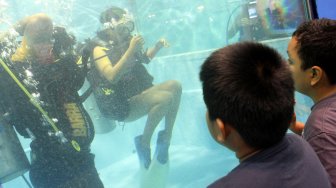 Pengunjung memperhatikan perlengkapan olahraga selam di Pameran Deep and Extreme Indonesia (DXI) 2019 di JCC, Jakarta, Jumat (5/4). [Suara.com/Arief Hermawan P]
