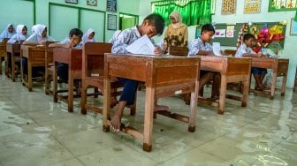 Sejumlah siswa SD kelas VI mengikuti ujian sekolah di ruang kelas yang terendam banjir di SD Negeri Sayung 4, Sayung, Demak , Jawa Tengah, Rabu (10/9). [ANTARA FOTO/Aji Styawan]