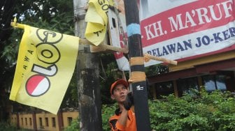 Sejumlah petugas PPSU menurunkan Alat Peraga Kampanye (APK) peserta Pemilu di Kawasan Imam Bonjol, Jakarta, Minggu (14/4). [Suara.com/Muhaimin A Untung]