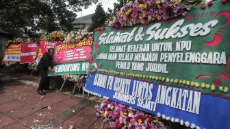 Petugas memasang karangan bunga di Kantor KPU, Jakarta, Minggu (21/4). [Suara.com/Muhaimin A Untung]