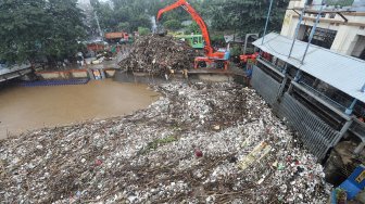 Alat berat melakukan pengangkatan sampah yang menumpuk di Pintu Air Manggarai, Jakarta, Rabu (24/4). [Suara.com/Muhaimin A Untung]
