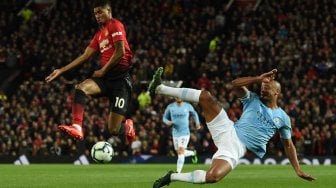 Bek Manchester City Vincent Kompany bersaing dengan pemain depan Manchester United Marcus Rashford selama pertandingan sepak bola Liga Premier Inggris antara Manchester United melawan Manchester City di Old Trafford, Manchester, Inggris, Kamis (25/4) dini hari WIB. [Oli SCARFF / AFP]