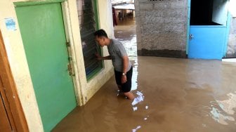 Warga memeriksa barang-barang didalam rumah yang tergenang banjir di kawasan Kampung Jawa, Pejaten Timur, Jakarta Selatan, Jumat (26/4). [Suara.com/Arief Hermawan P]