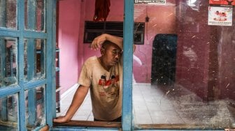 Warga bersandar di jendela usai membersihkan rumahnya dari lumpur pascabanjir di kawasan Kelurahan Rawajati, Jakarta, Senin (29/4). ANTARA FOTO/Muhammad Adimaja