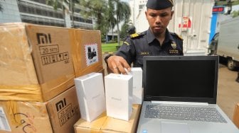 Polisi dan Petugas Direktorat Jenderal Bea Cukai memperlihatkan barang bukti saat rilis Hasil Penindakan Telepon Genggam, Tablet, Laptop dan Alat Elektronik di Lapangan Hitam Parkiran Kantor Pusat Direktorat Jenderal Bea dan Cukai, Jakarta, Selasa (30/4). [Suara.com/Muhaimin A Untung]