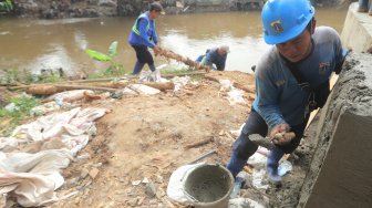 Sejumlah pasukan Sumber Daya Air DKI Jakarta memperbaiki tanggul sungai Ciliwung, Jakarta, Jumat (3/5).[Suara.com/Muhaimin A Untung]