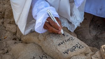 Peziarah menuliskan nama kerabatnya di kawasan bukit Jabal Rahmah, Padang Arafah, Makkah Al Mukarramah, Arab Saudi, Sabtu (4/5). ANTARA FOTO/Aji Styawan