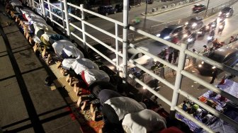 Umat muslim menunaikan ibadah shalat Tarawih pertama di JPO dan halaman Musholla Miftahul Janah, Pasar Gembrong, Jakarta, Minggu (5/5). [Suara.com/Arief Hermawan P]