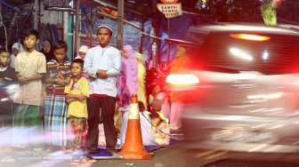 Umat muslim menunaikan ibadah shalat Tarawih pertama di JPO dan halaman Musholla Miftahul Janah, Pasar Gembrong, Jakarta, Minggu (5/5). [Suara.com/Arief Hermawan P]