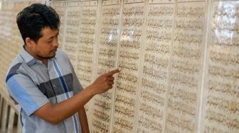 Warga mengamati ukiran huruf Al Quran di batu marmer di Masjid Al Muhtarom, Kabupaten Pekalongan, Jawa Tengah, Minggu (12/5). [ANTARA FOTO/Harviyan Perdana Putra]