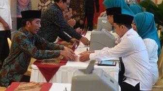 Presiden Joko Widodo (kiri) menyerahkan pembayaran zakat mal kepada petugas di Istana Negara, Jakarta, Kamis (16/5). [ANTARA FOTO/Akbar Nugroho Gumay]