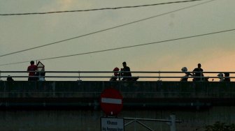 Sejumlah warga menunggu waktu berbuka puasa di Flyover Pasar Rebo, Kamis (16/5). [Suara.com/Muhaimin A Untung]