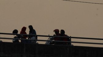 Sejumlah warga menunggu waktu berbuka puasa di Flyover Pasar Rebo, Kamis (16/5). [Suara.com/Muhaimin A Untung]