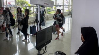 Penumpang pesawat melintasi alat pendeteksi suhu tubuh (thermal scanner) saat tiba di terminal 2 Bandara Juanda Surabaya di Sidoarjo, Jawa Timur, Jumat (17/5). [ANTARA FOTO/Umarul Faruq]