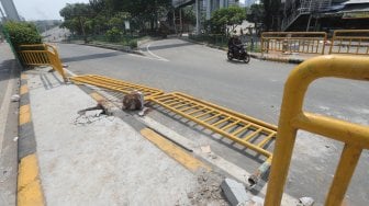 Kendaraan melintas di samping pembatas jalan yang rusak di Kawasan Tanah Abang, Jakarta, Rabu (22/5). [Suara.com/Muhaimin A Untung]