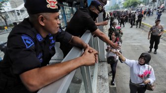 Sejumlah anggota komunitas Spartan Nusantara memberi bunga ke petugas kepolisian saat aksi dukungan di depan kantor Bawaslu, Jakarta, Minggu (26/5). [Suara.com/Muhaimin A Untung]