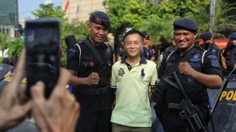 Warga berfoto dengan petugas polisi di Gedung Badan Pengawas Pemilu (Bawaslu) saat Hari Bebas Kendaraan Bermotor di kawasan Sarinah, Jakarta, Minggu (26/5). [Suara.com/Muhaimin A Untung]