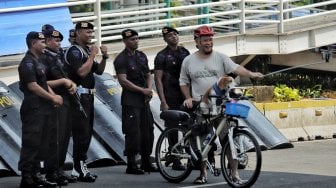 Warga berfoto dengan petugas polisi di Gedung Badan Pengawas Pemilu (Bawaslu) saat Hari Bebas Kendaraan Bermotor di kawasan Sarinah, Jakarta, Minggu (26/5). [Suara.com/Muhaimin A Untung]