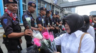 Sejumlah anggota komunitas Spartan Nusantara memberi bunga ke petugas kepolisian saat aksi dukungan di depan kantor Bawaslu, Jakarta, Minggu (26/5). [Suara.com/Muhaimin A Untung]